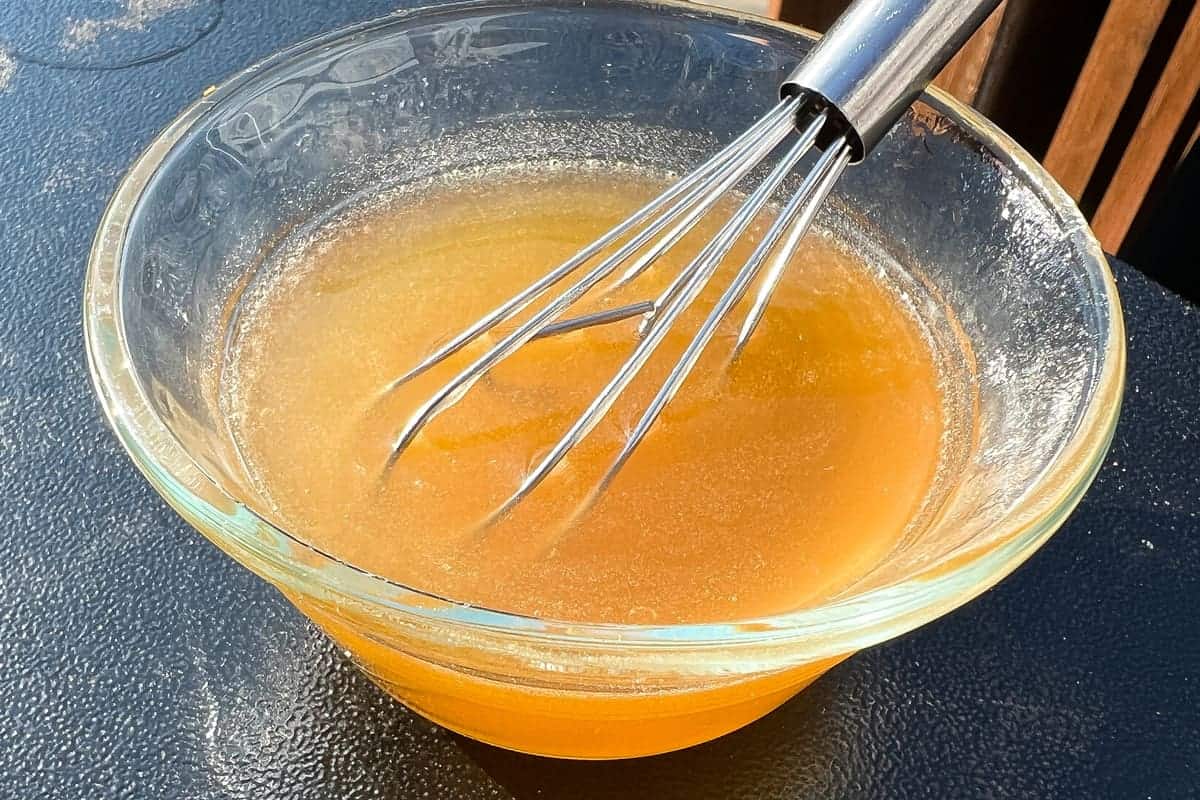 honey glaze in a small glass bowl with a small wire whisk