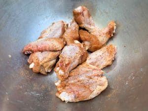 raw chicken wings in a bowl with BBQ rub