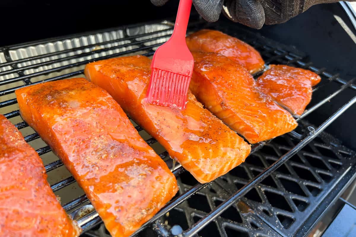 honey glaze being basted onto a salmon fillet