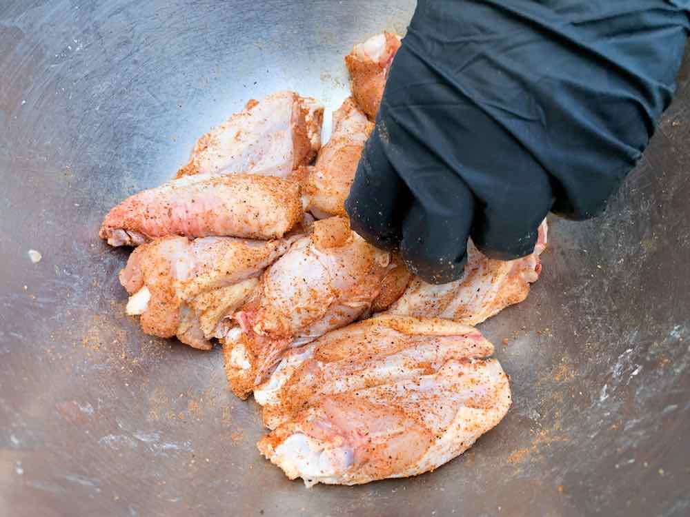tossing raw chicken wings with baking powder and bbq rub