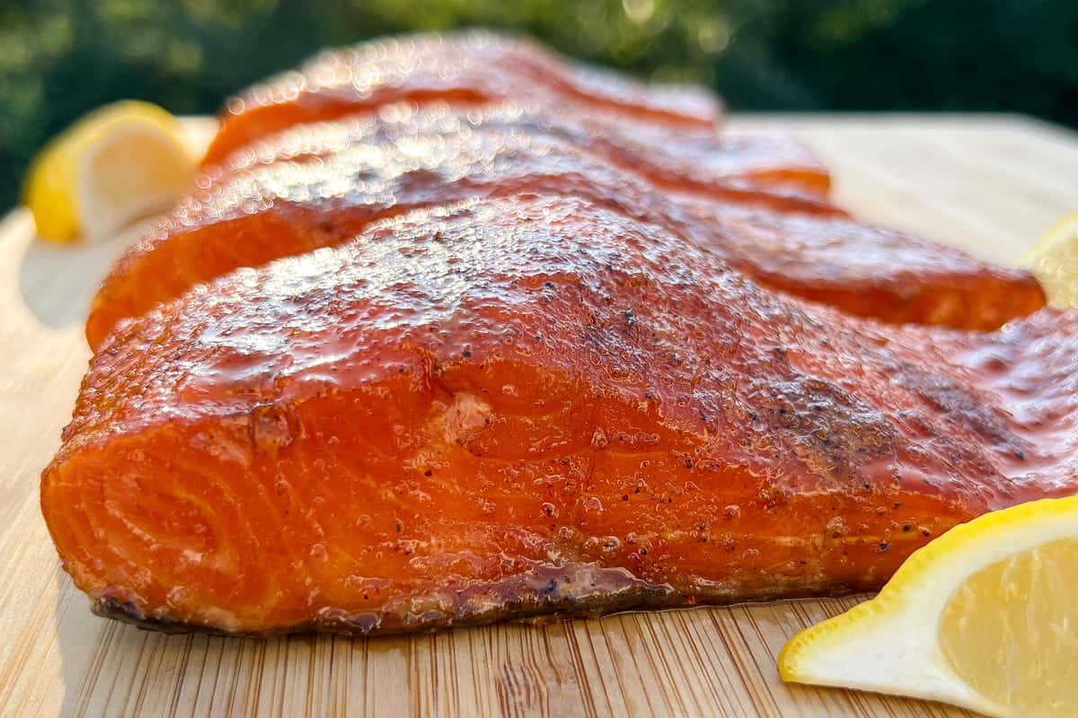 smoked salmon on a cutting board with lemon wedges