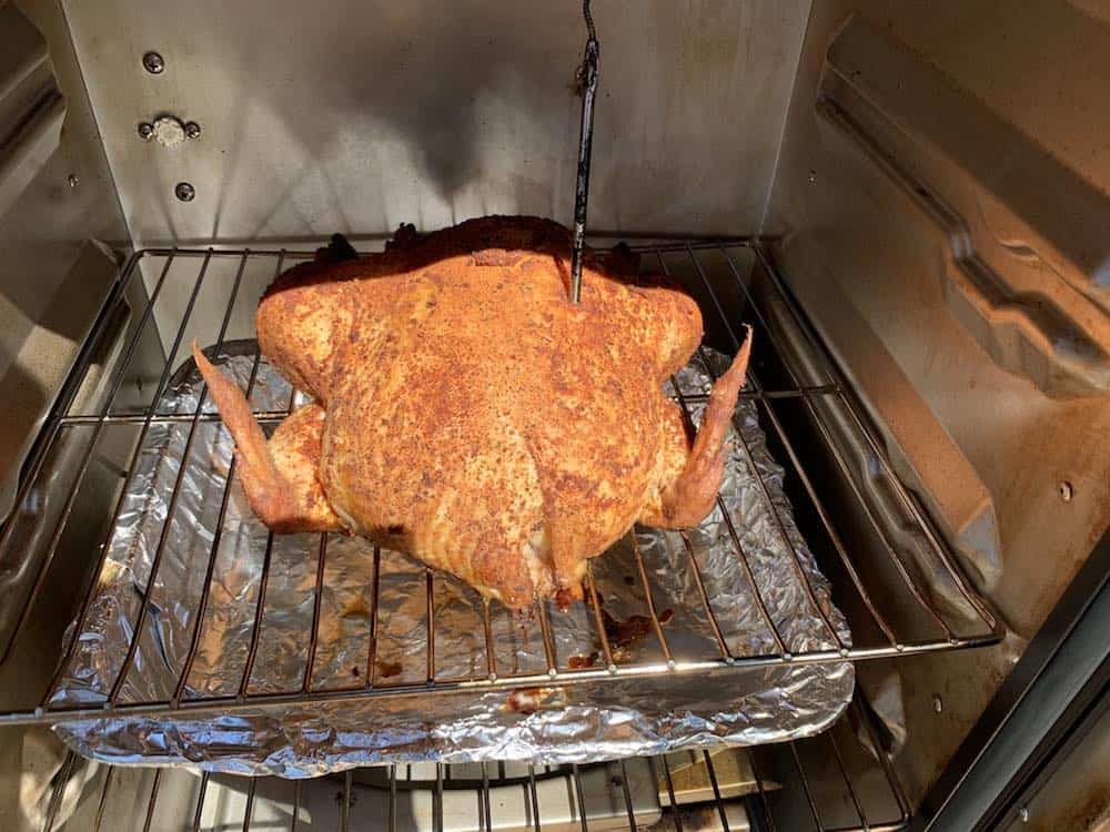 a smoked whole chicken with a temperature probe in a masterbuilt electric smoker
