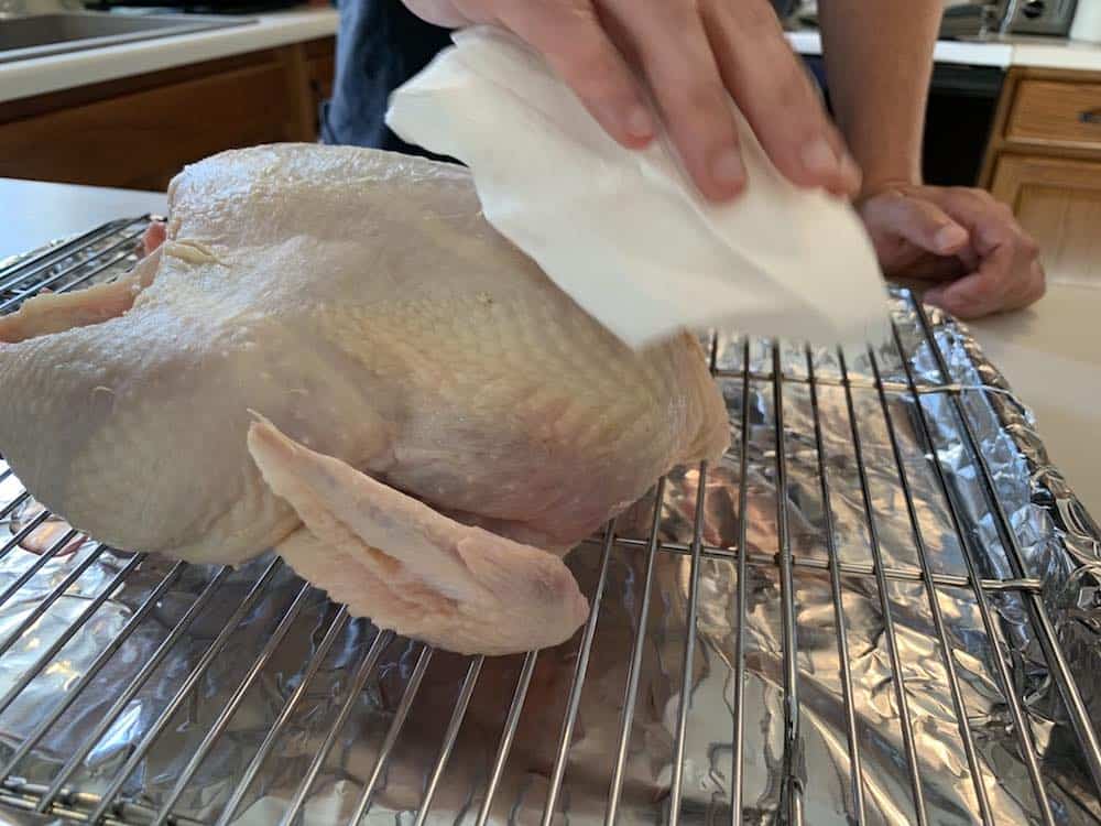 patting a raw whole chicken dry with paper towels