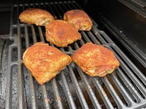 seasoned chicken thighs smoking on a traeger pellet grill