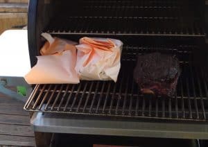 beef ribs wrapped in pink butcher paper on a traeger pellet grill