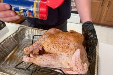 raw turkey being sprinkled with Famous Dave's chicken rub