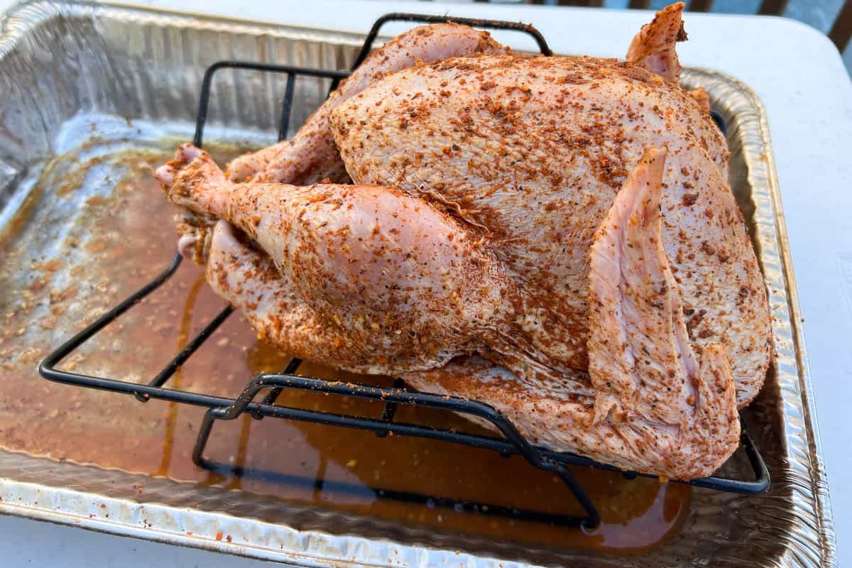 dry brined turkey in a v shaped rack inside an aluminum foil pan