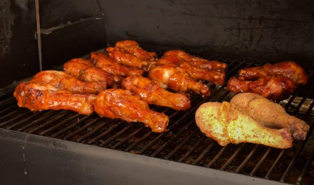 sauced chicken legs smoking on a traeger pellet grill