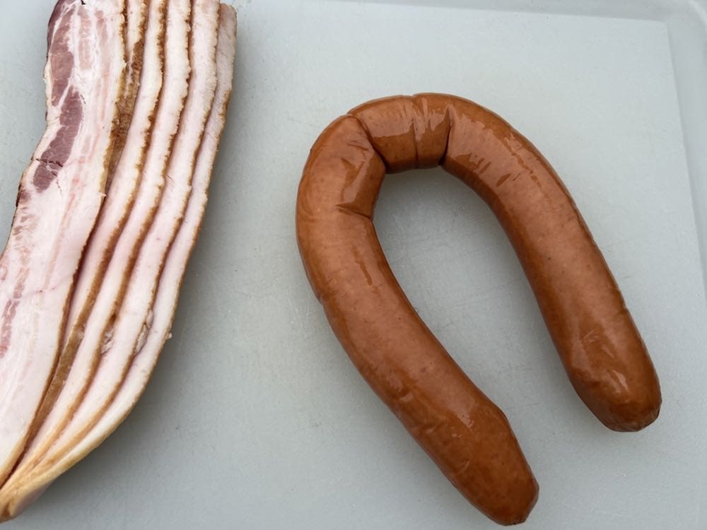 bacon and kielbasa for pig shots on a cutting board