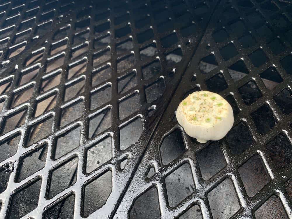 a head of garlic smoking on a grill
