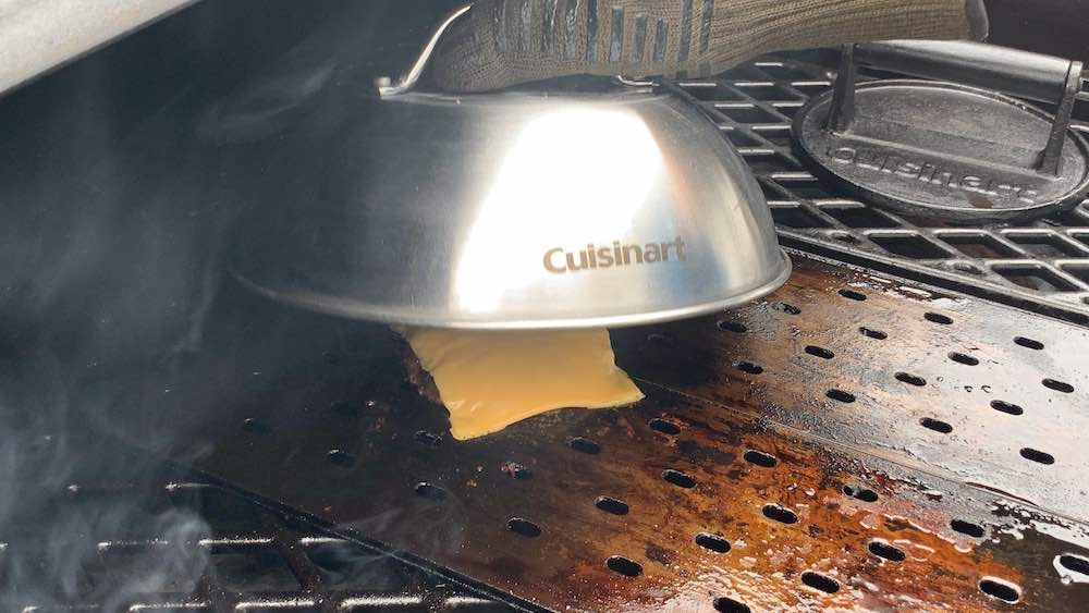 Cuisinart melting dome covering a cheeseburger on grill grates