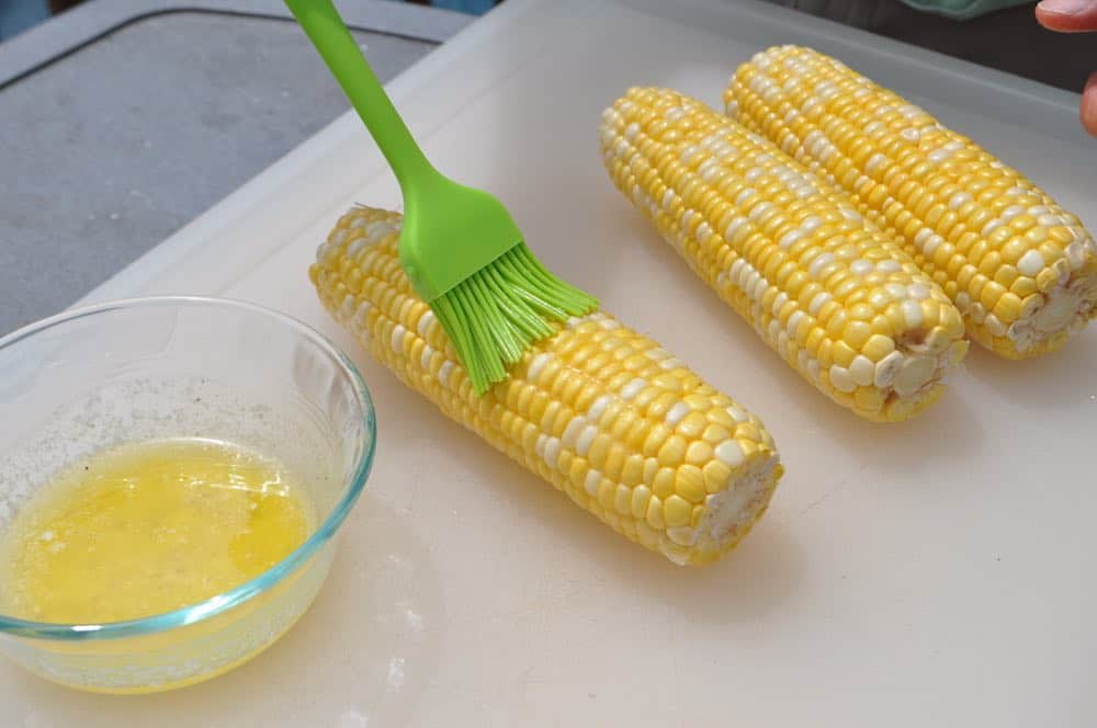 basting seasoned butter on corn on the cob before smoking