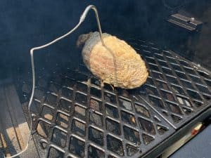 a raw boneless turkey breasts msoking on a pit boss pellet grill with a temperature probe inside