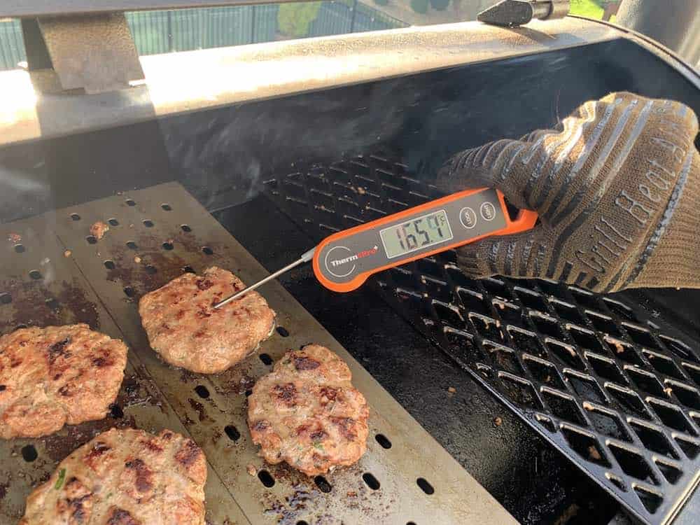 checking the temperature of finished smoked turkey burgers at 165 degrees