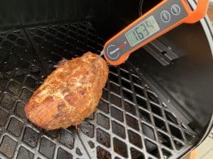 using an instant thermometer on a smoked boneless skinless turkey breast on a pit boss pellet grill