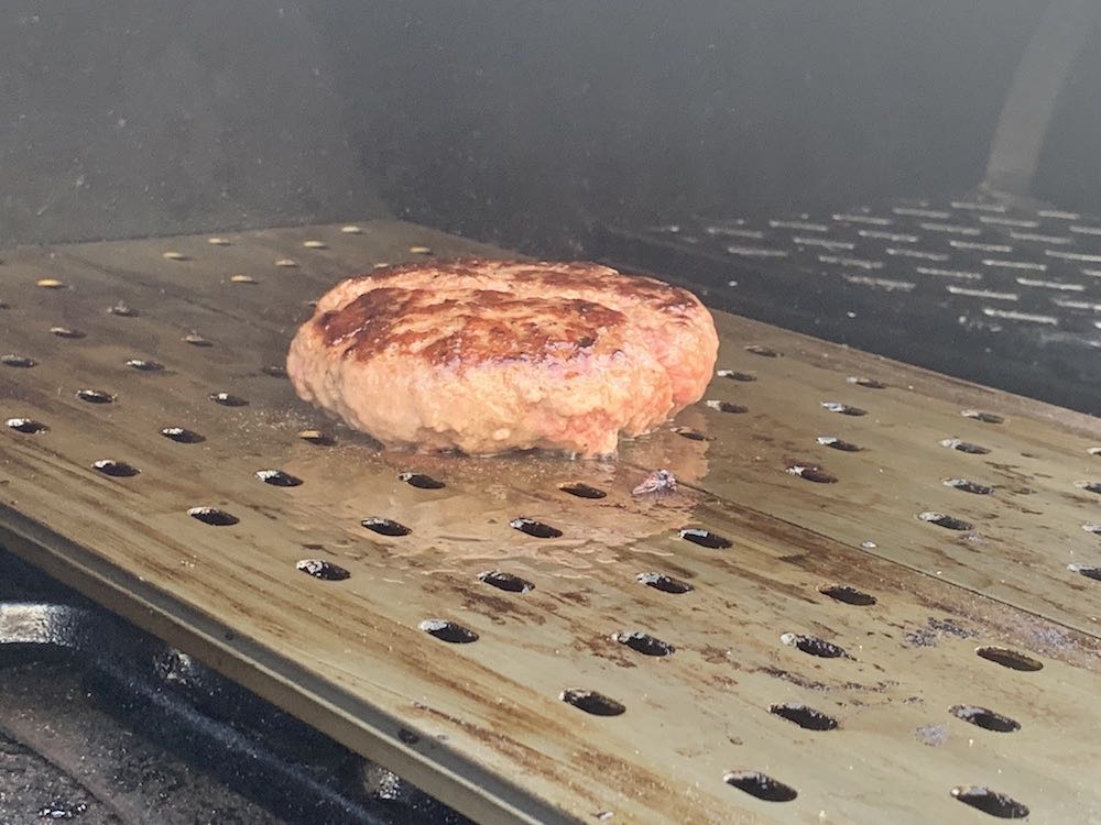 a hamburger cooking a grill grate