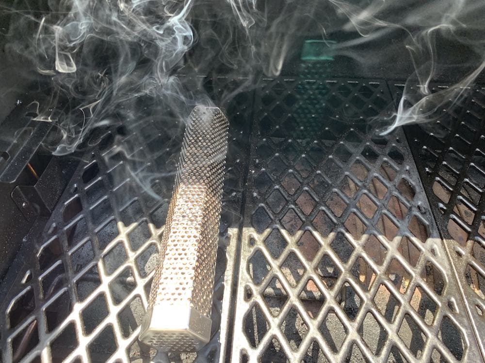 a lit pellet smoker tube making smoke on a grill