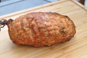 a pit boss smoked boneless turkey breast on a cutting board with ties still on