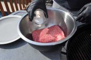 seasoning ground beef in a bowl with salt