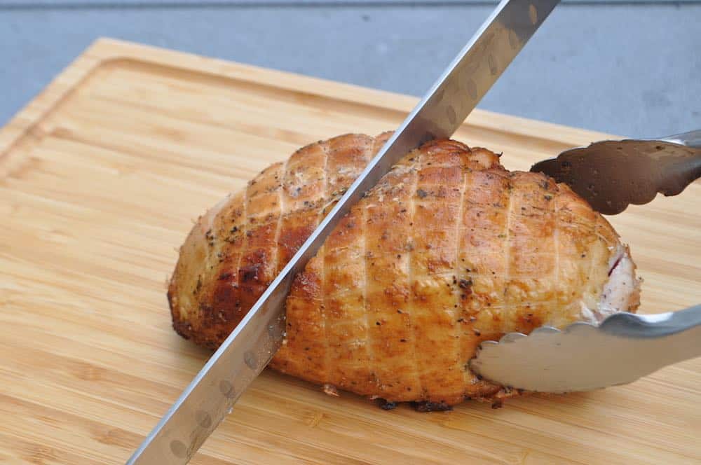 slicing a pit boss smoked boneless turkey breast on a cutting board