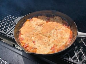 a smoked peach cobbler in a cast iron skillet