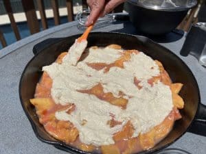 spreading dough on top of peach cobbler