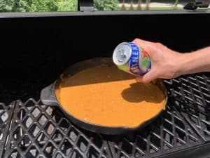 adding beer to a pit boss smoked skillet queso dip