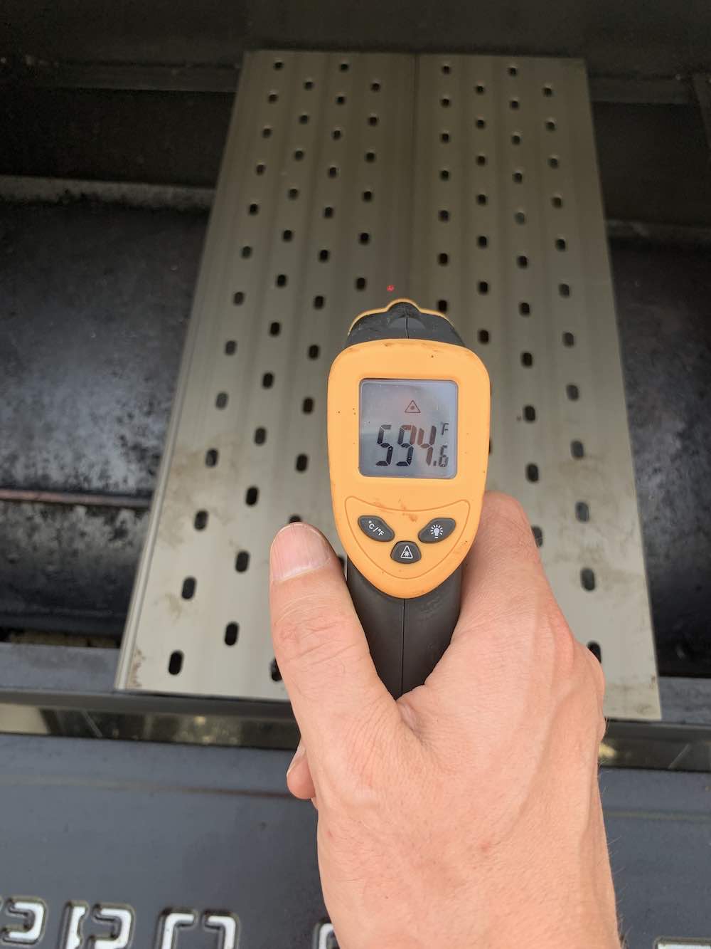 checking the temperature of a grill grate with an infrared thermometer
