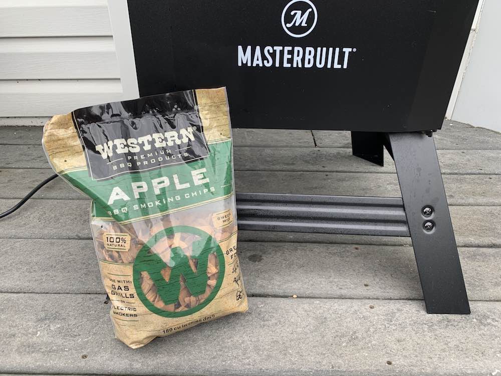 apple wood chips propped in front of a masterbuilt electric smoker