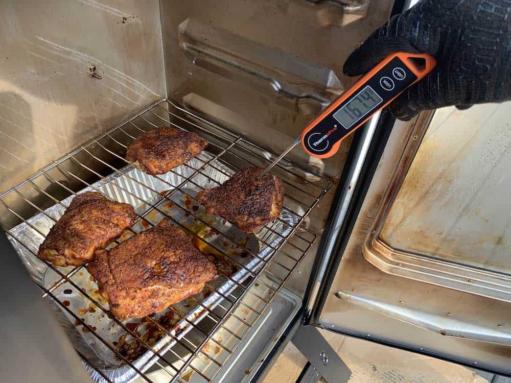 checking the internal temperature of electric smoker smoked chicken thighs
