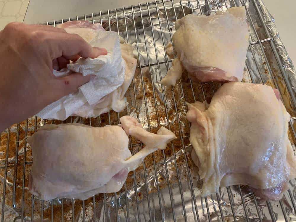 patting raw chicken thighs dry with a paper towel