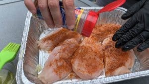 sprinkling seasoning on chicken breasts