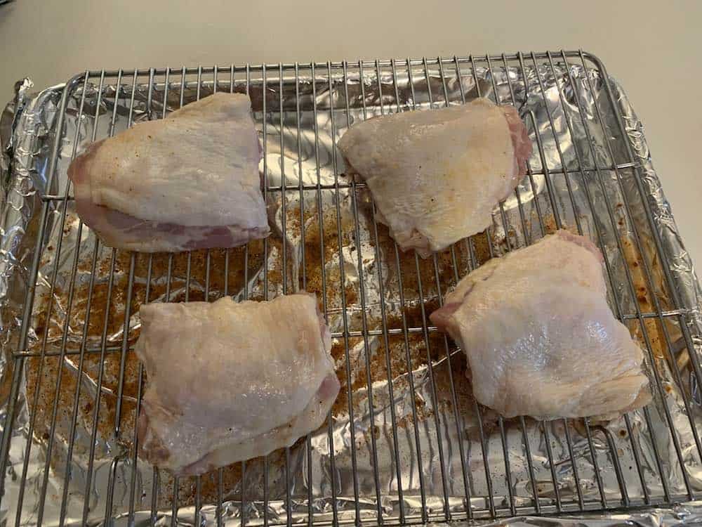 raw trimmed chicken thighs on a wire rack
