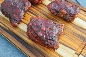 electric smoker smoked chicken thighs on a cutting board