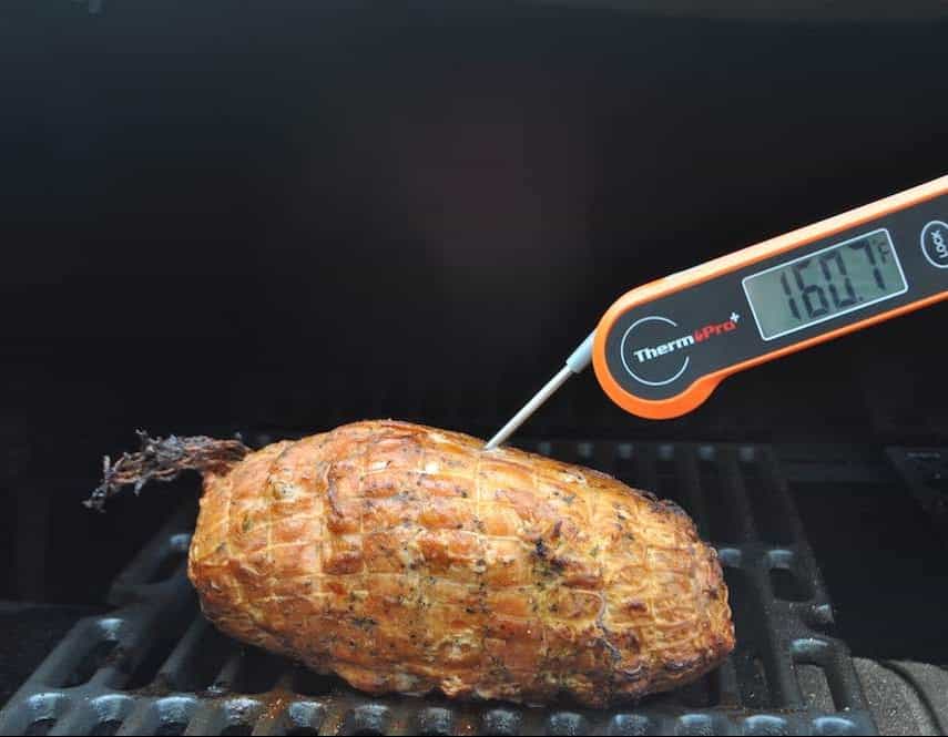 checking the temperature of a smoked boneless turkey breast on a traeger pellet grill