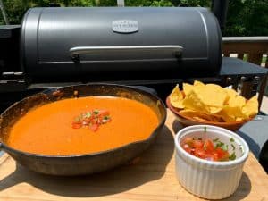 a smoked queso dip in front of a pit boss pellet grill