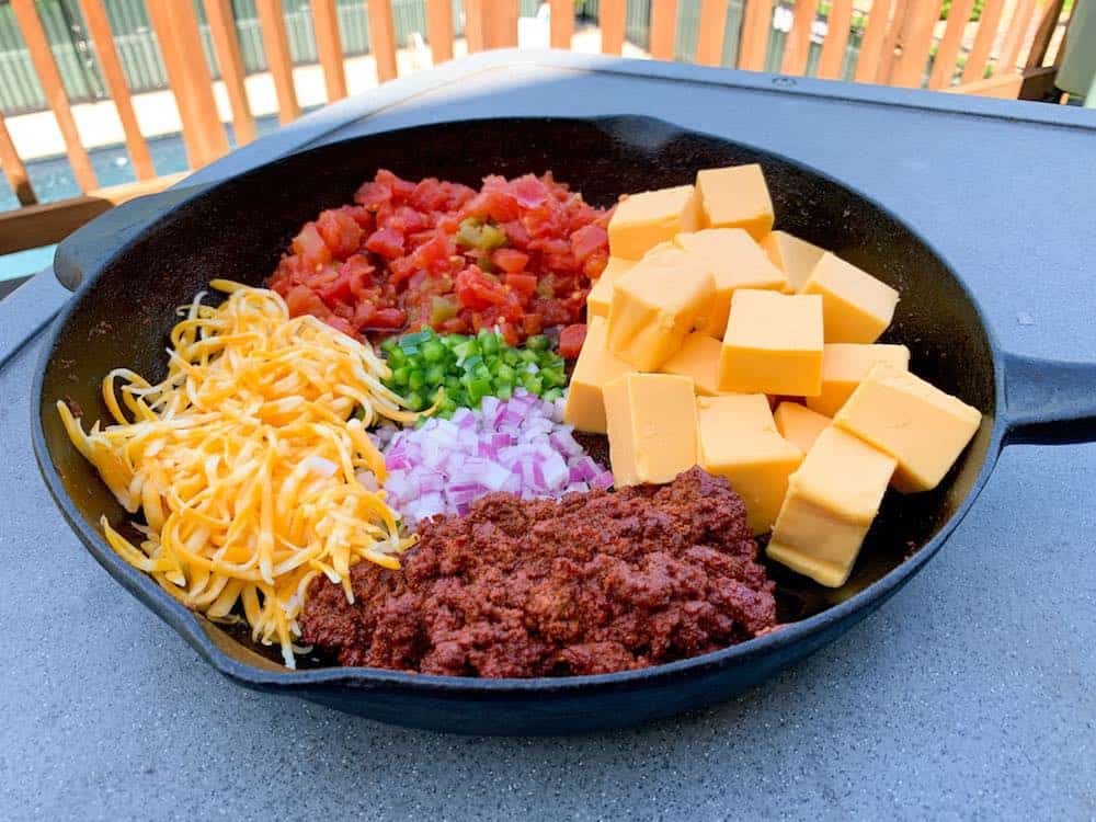 smoked queso ingredients laid out in a cast iron skillet
