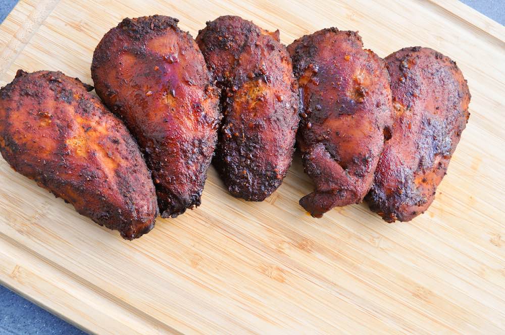 electric smoker smoked chicken breasts on a cutting board