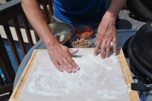 spreading out smoked pizza dough with hands