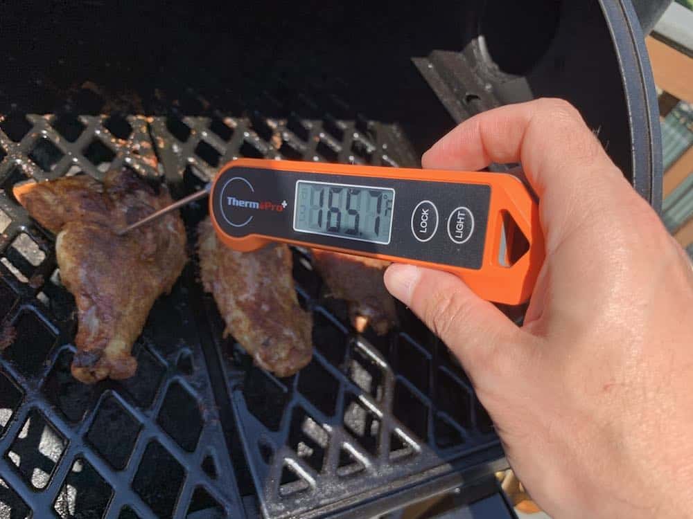 an instant read thermometer showing 165 degrees on smoked turkey wings