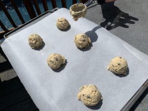 scooping balls of chocolate chip cookie dough onto a baking sheet