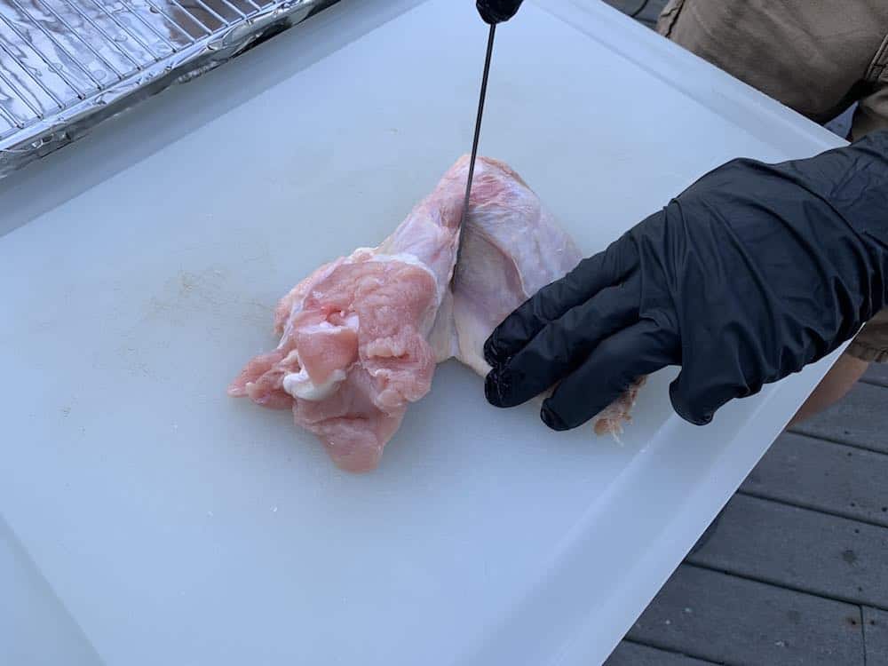 separating a raw turkey wing with a knife