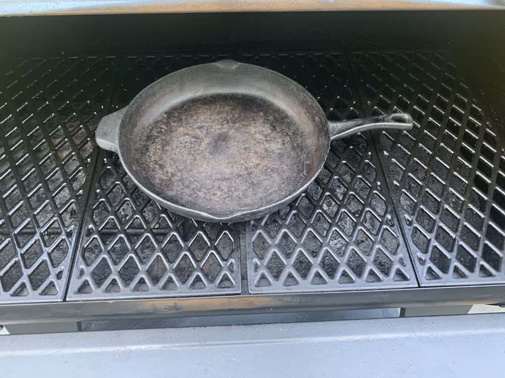 a cast iron skillet preheating on a grill
