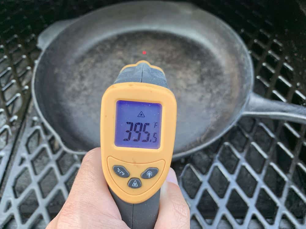 an infrared thermometer showing a preheated cast iron skillet at 395 degrees F