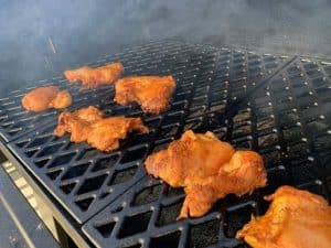 chicken thighs smoking on a pellet grill for smoked chicken tacos