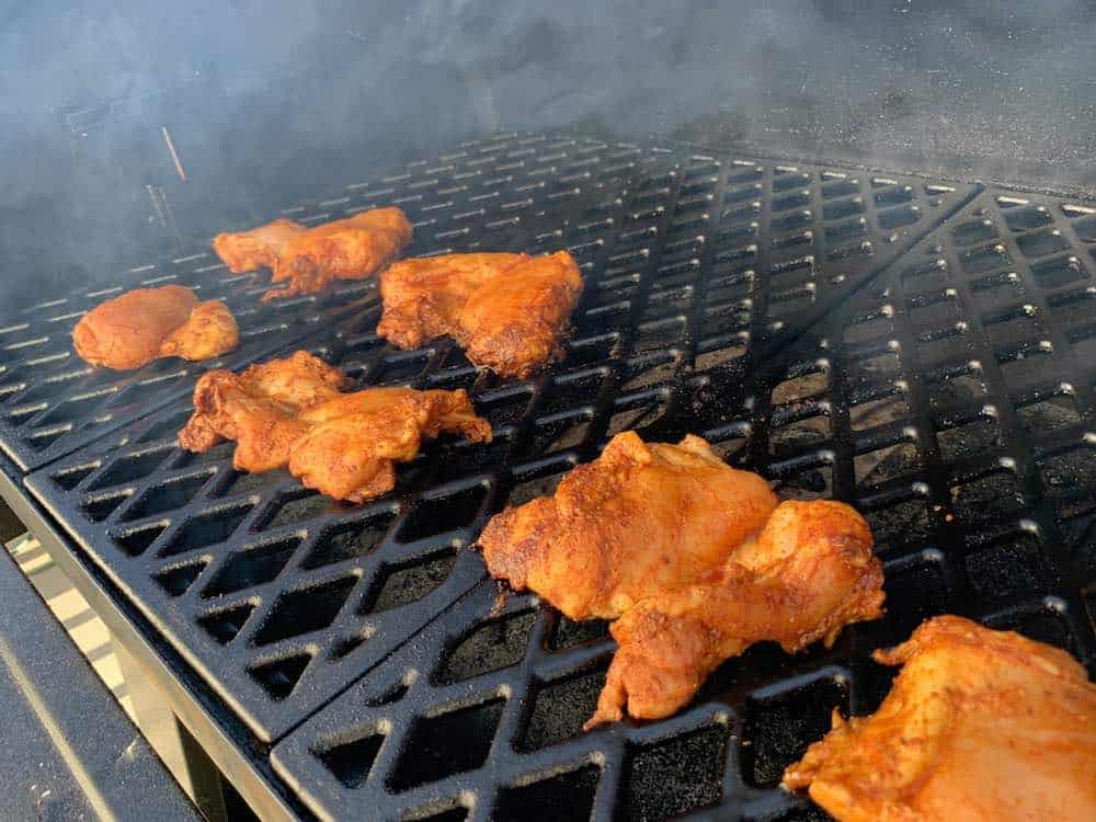 chicken thighs smoking on a pellet grill for smoked chicken tacos