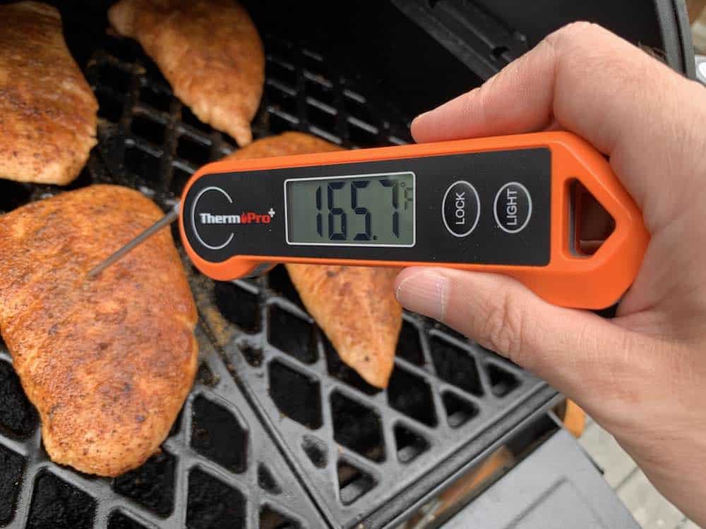 an instant thermometer showing 165 degree internal temperature of a smoked turkey tenderloin