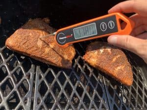 an instant read thermometer showing 178 degrees internal temperature of smoked turkey thighs