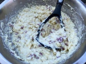 mashing smoked potatoes in a mixing bowl