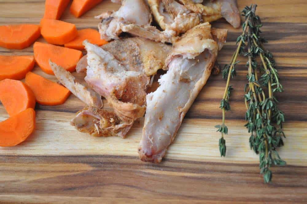 a cutting board with smoked turkey, carrots, and herbs